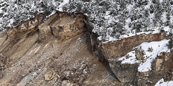 Overhanging cliff face at top of collapsed slope of limestone quarry.